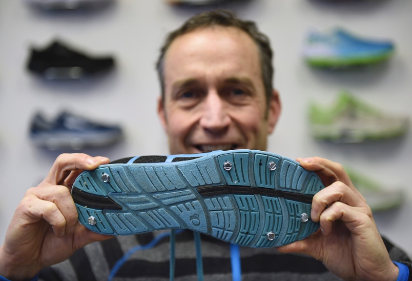 Dave Cressman of Distance Runwear shows running shoes with metal studs for running on snow