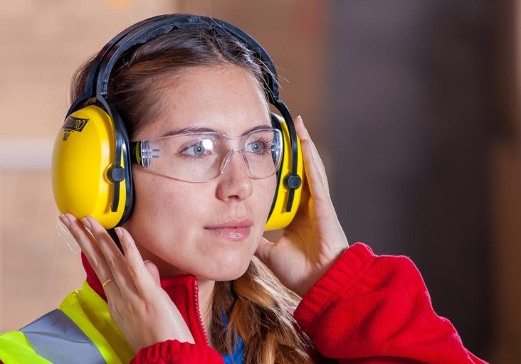 Woman wearing personal protective equipment eye goggles and ear covers