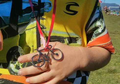Youth participant of bike race wearing metal bike award manufactured by Hansen Industries